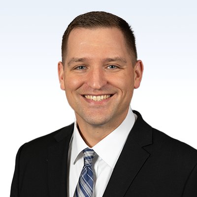 Joseph Motzko, hearing care professional, wearing a suit and tie against a light background.
