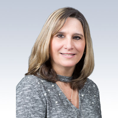 judith pierce, hearing care specialist dressed in a gray sweater with pearl details