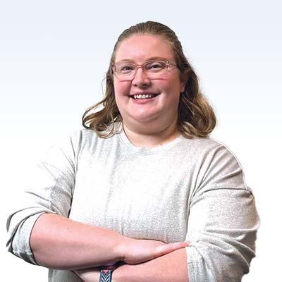 Hearing care professional with crossed arms against a white background.