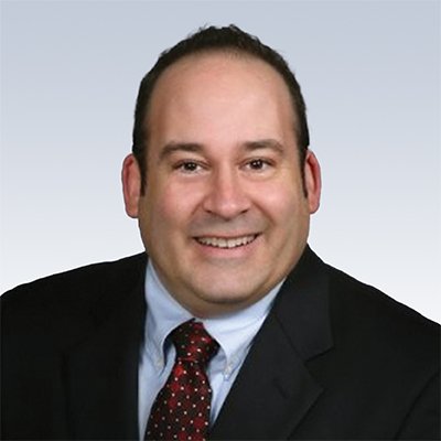 Professional man in a suit and tie against a gradient background.