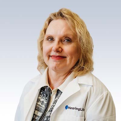 Hearing care specialist wearing a HearingLife lab coat with a blurred face.