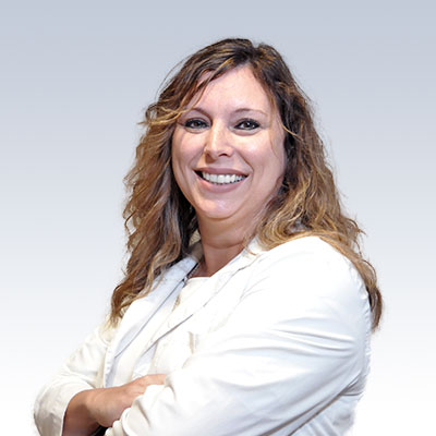 Lisa Haeuser standing with arms crossed, wearing a white coat against a gradient background.