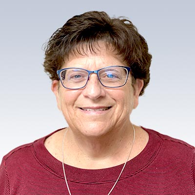 Lori Leiman wearing a red top against a gradient background.