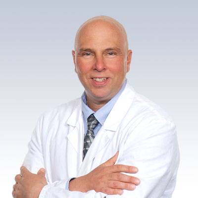 Louis Columbus, hearing care professional wearing a white coat against a gradient background.