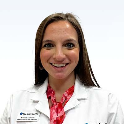 Hearing specialist Mackenzie Connor wearing a white lab coat and red scarf.