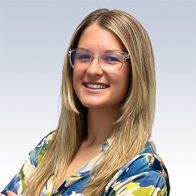 Paige Wendling, hearing care professional, wearing glasses and a colorful blouse against a light gradient background.