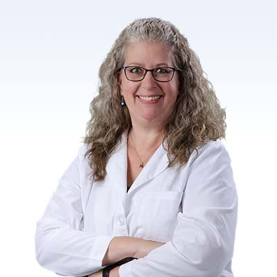 Hearing care professional in a white lab coat with arms crossed.