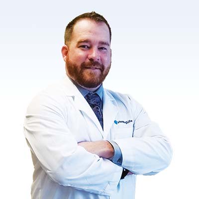 Patrick Quane, hearing care specialist in a white lab coat, arms crossed.