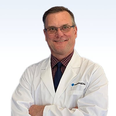 Hearing care professional Patrick Risko wearing a white coat with the HearingLife logo.