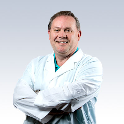 Paul Magnusson wearing a white lab coat with arms crossed against a gradient background.