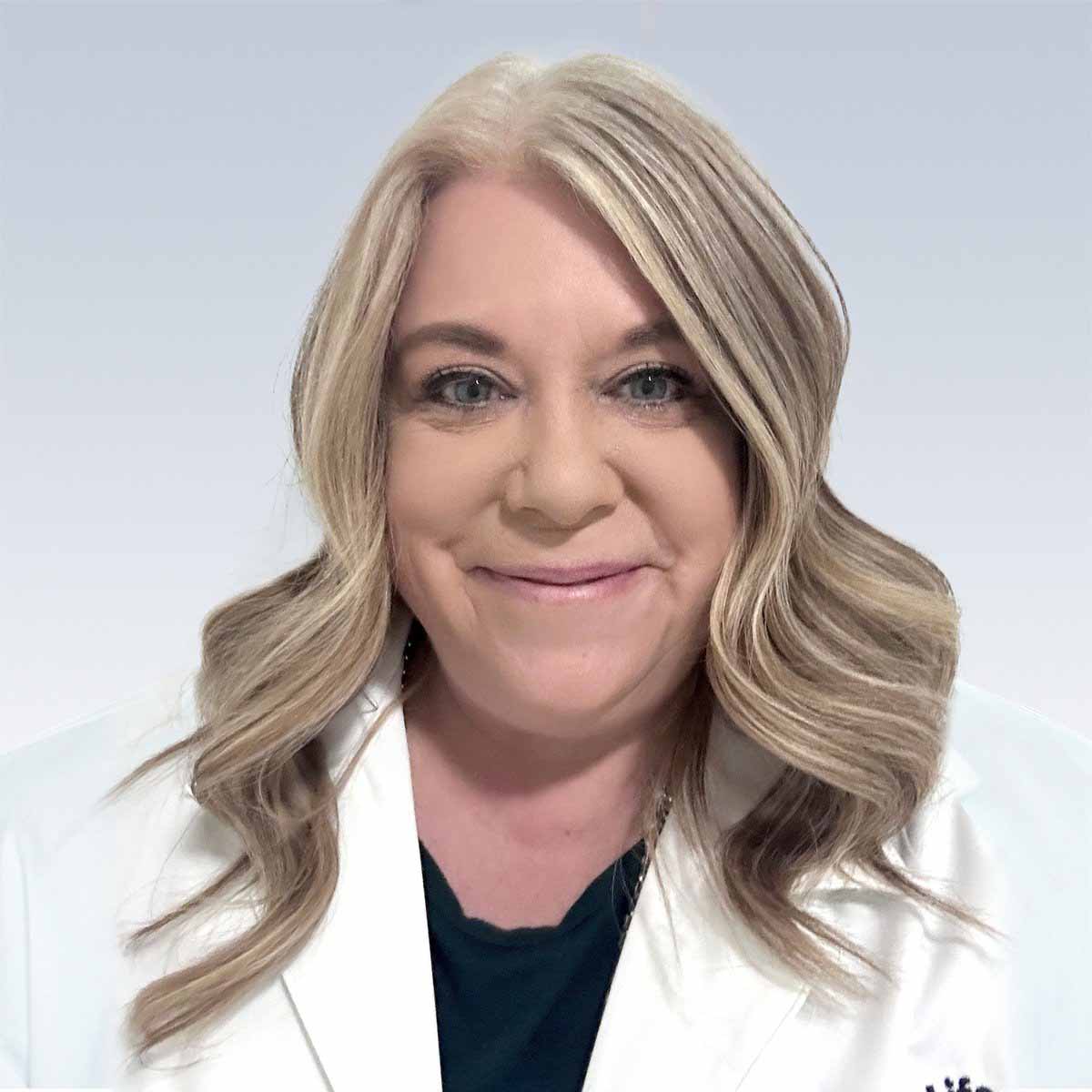 Raechelle Martin, hearing care professional wearing a white coat with wavy blonde hair.