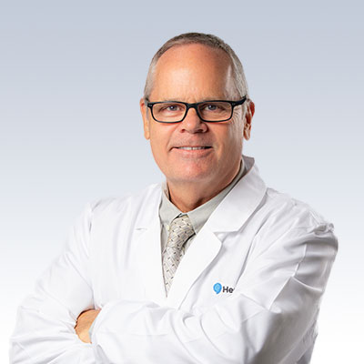 Hearing care professional in a white coat with a folded arms stance.