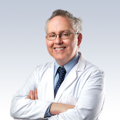 Hearing care professional in a white coat with arms crossed, representing expertise in hearing health.