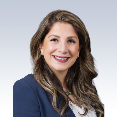 Romina Seferian, hearing care professional, in formal attire against a gradient background.