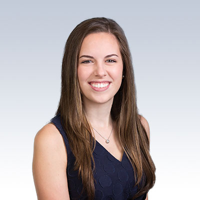 Dr. Samantha Hartnett wearing a navy sleeveless top against a gradient background.