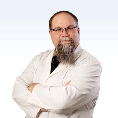 Hearing care professional wearing a white lab coat with arms crossed.