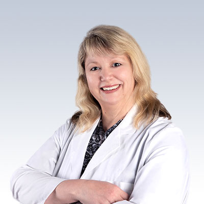 Hearing care professional wearing a white coat with arms crossed.