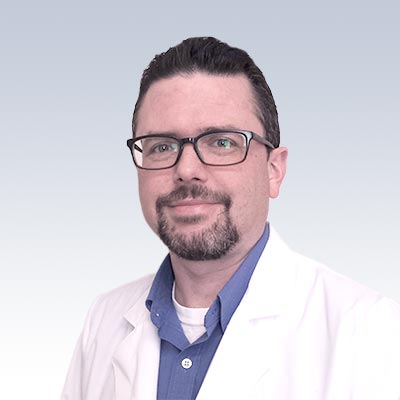 Theodore Bunn wearing a white lab coat and blue shirt.