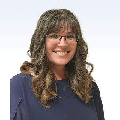 Toni Frederick, hearing care professional, wearing a navy blouse against a light background.