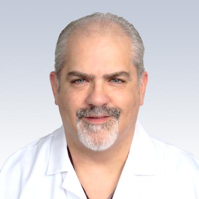 William Yost wearing a white lab coat against a gradient background.