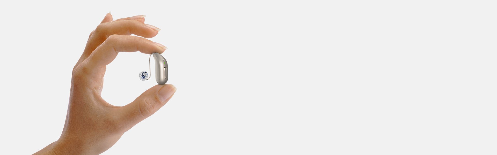 modern hearing aid with a discreet design held between a woman's fingers