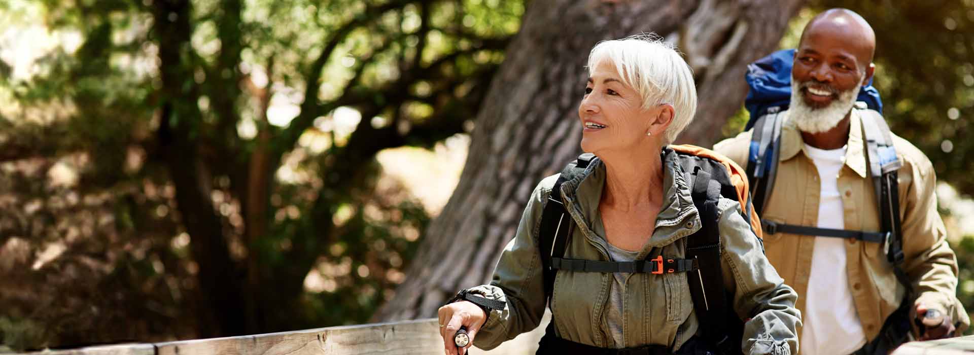 Older adults hiking through a forest, appreciating nature and ambient outdoor sounds.