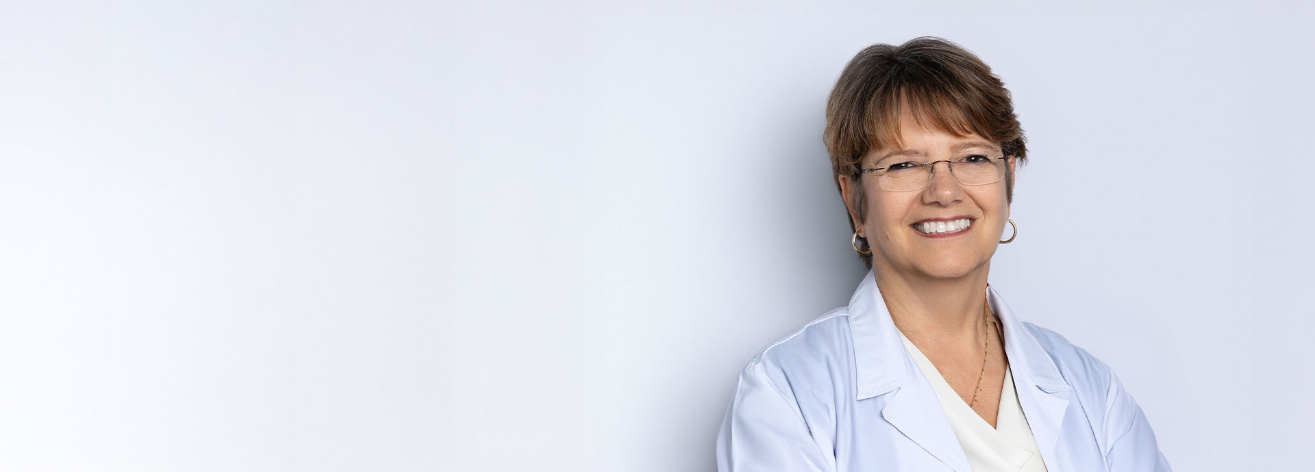 HearingLife Chief Audiologist Leslie Soiles wearing a white lab coat and smiling.