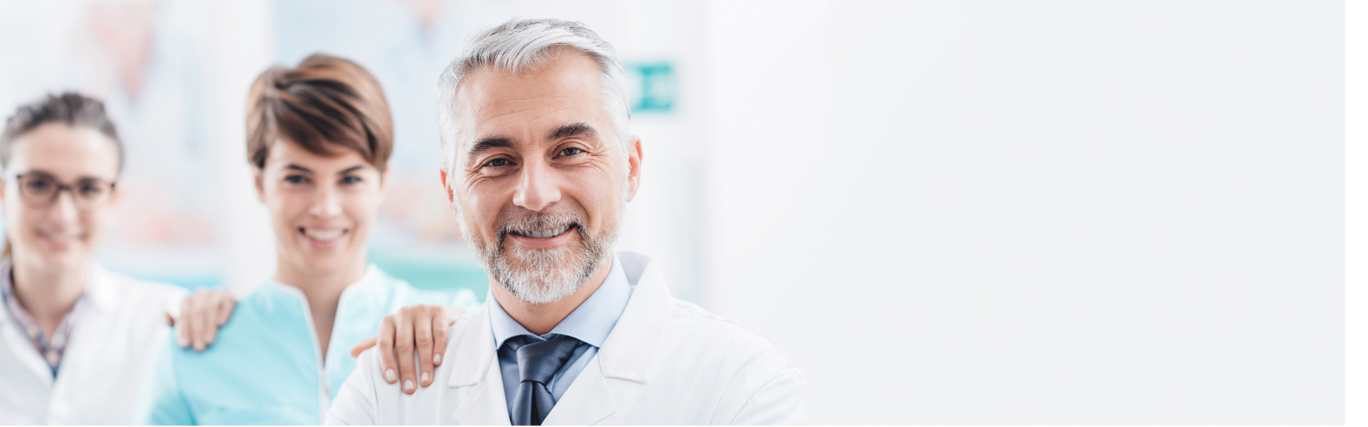Hearing care professionals smiling and standing together in a clinic environment.