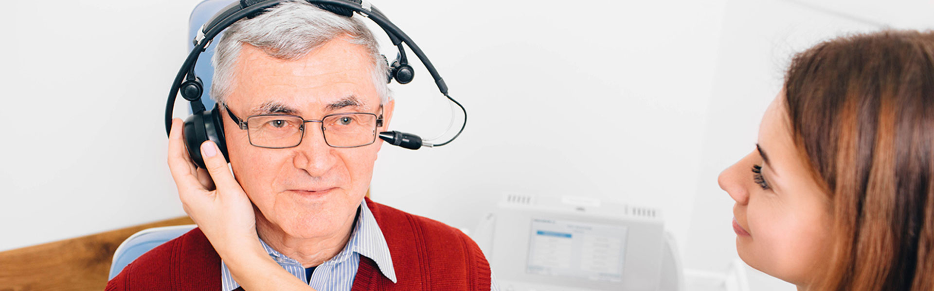 Man having a hearing test with headphones conducted by a hearing care professional at a hearing clinic.