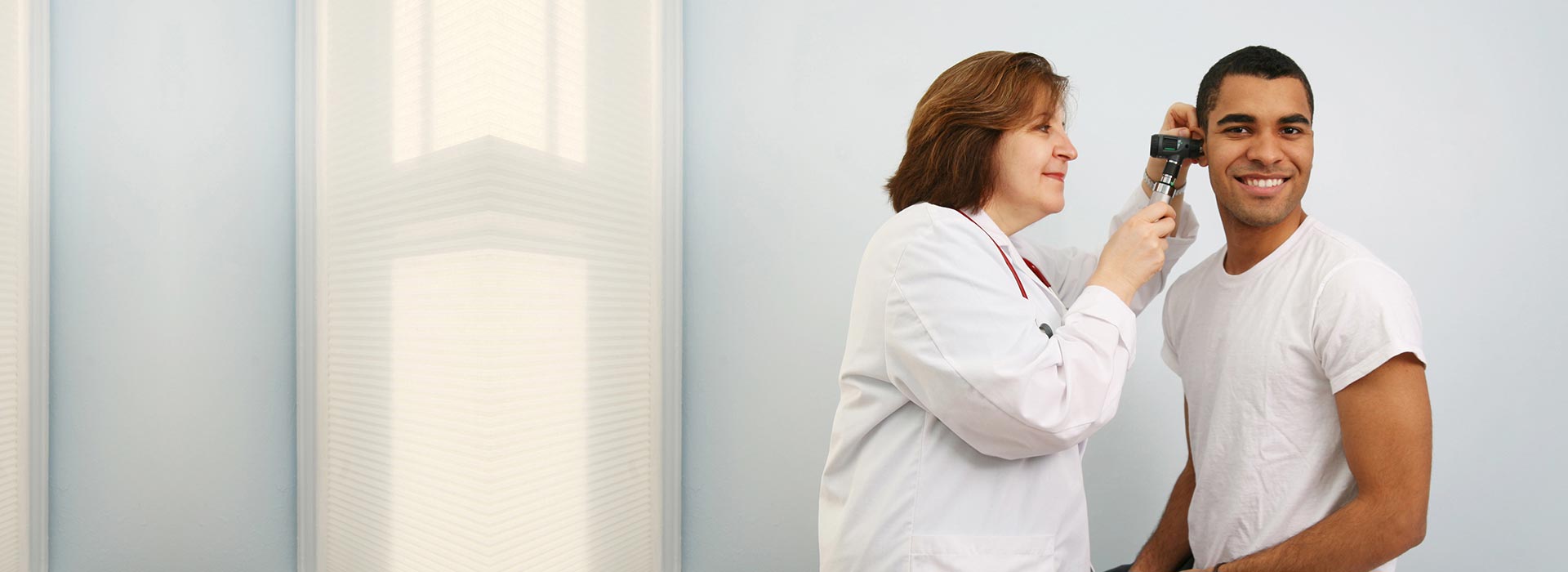 Audiologist examining a patient's ear with an otoscope.