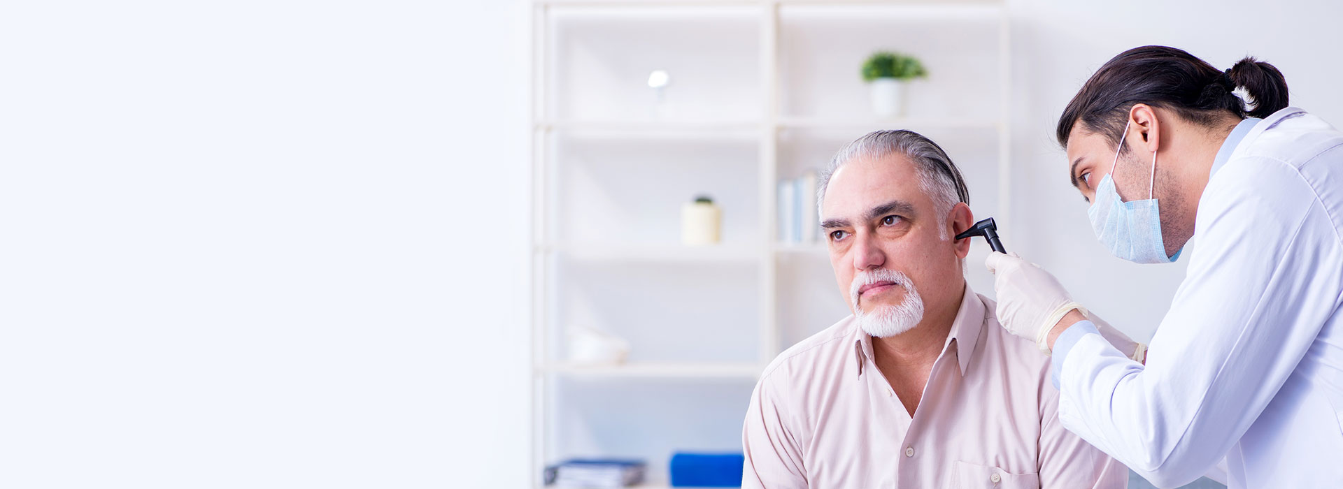Audiologist performing an ear examination on a patient in a clinic setting.