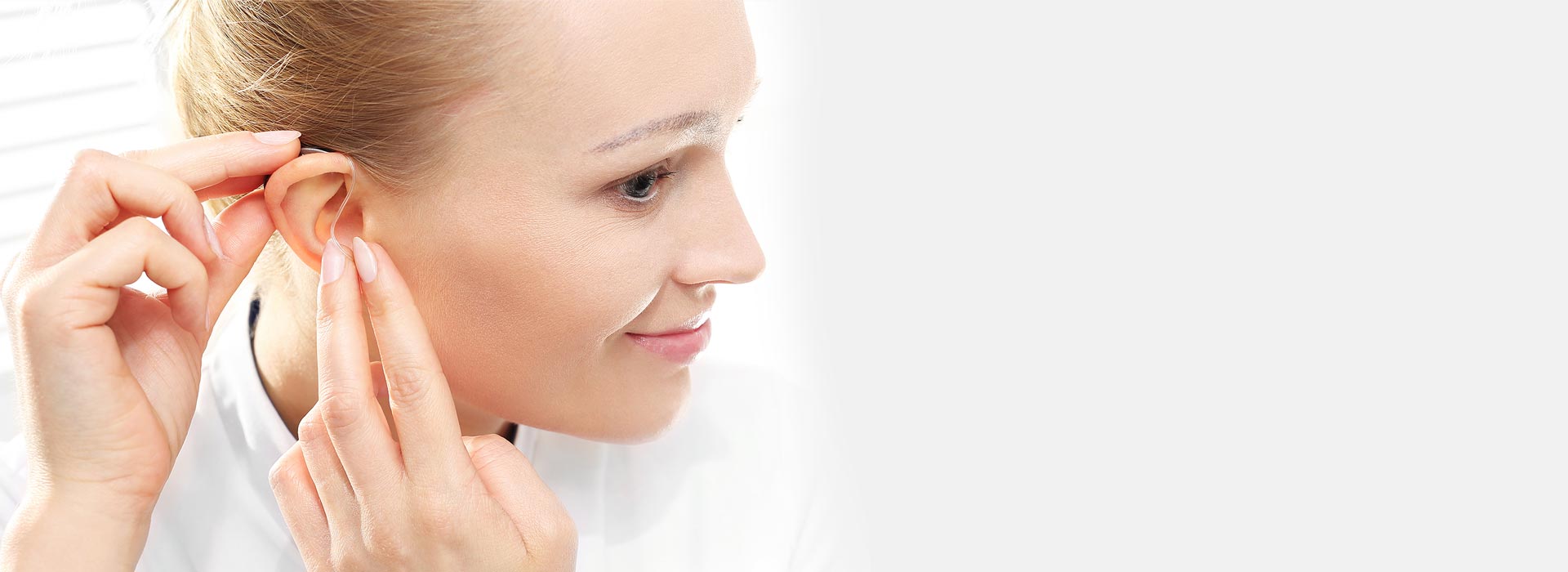 Woman inserting a behind-the-ear hearing aid.