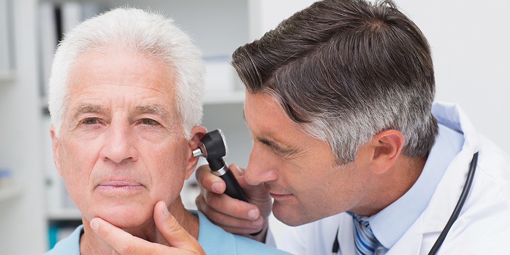 Audiologist examining a patient's ear with an otoscope