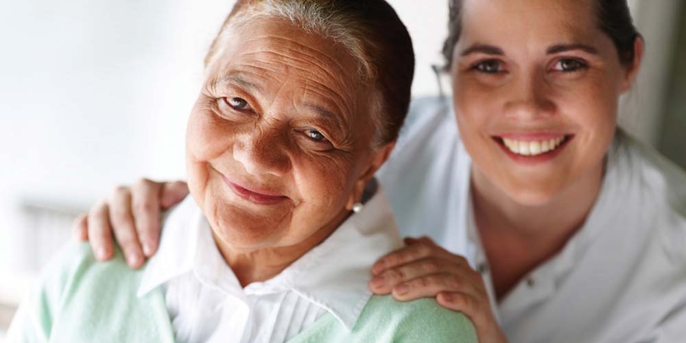 Nurse comforting senior resident with a supportive embrace