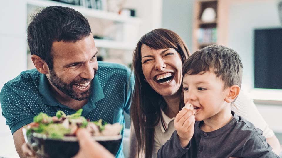 Family sharing laughter and enjoying time together over a meal.