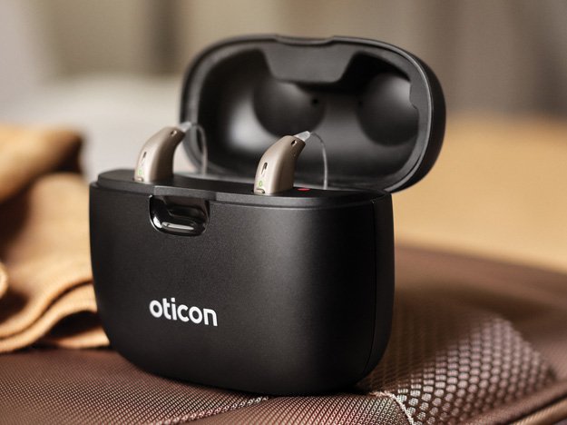 Oticon Real™ travel charger with two hearing aids placed inside, designed for convenient on-the-go charging.
