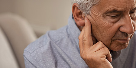 Man touching his ear, appearing to experience a sensation of clogged ears.