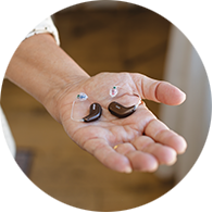 a pair of behind the ear hearing aids in a hand
