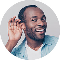 Smiling man holding hand behind ear to indicate active listening.