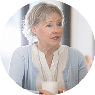Senior woman holding a cup while engaging in a conversation.
