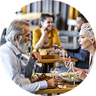 Older couple dining at a restaurant with friends, engaged in conversation.