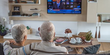 Senior couple watching television together in a cozy living room.