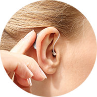 behind-the-ear hearing aid being adjusted on a person's ear