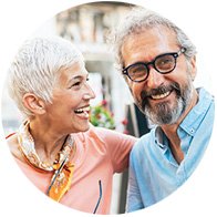 Happy couple embracing outdoors while wearing discreet Oticon Own hearing aids
