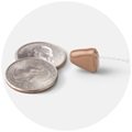 Oticon Own hearing aid positioned next to two quarters for size reference