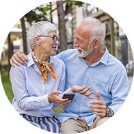 Happy senior couple smiling and sitting outdoors while sharing a moment together.