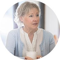 Senior woman holding a cup while engaging in a conversation.