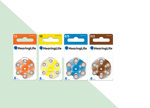 Four packs of HearingLife hearing aid batteries are lined up side by side, each labeled with different color codes (13, 10, 675, 312) containing 6 batteries per pack.