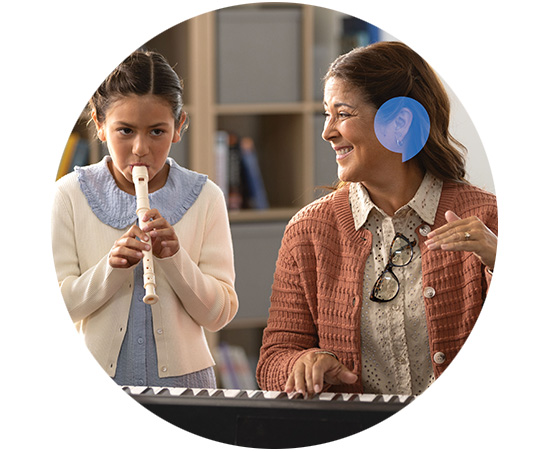 music teacher smiling at student playing recorder instrument