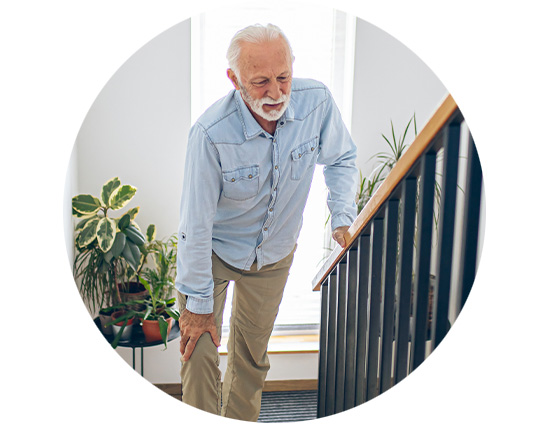 Senior man navigating stairs while holding the railing, appearing to struggle with balance.